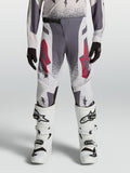 Alpinestars 2027 Supertech Swan ungdomsbyxor, motocrossbyxor för tävling, gråa och lila med röda detaljer, atletisk passform i stretch-ripstop, bärs med vita stövlar för terrängkörning.