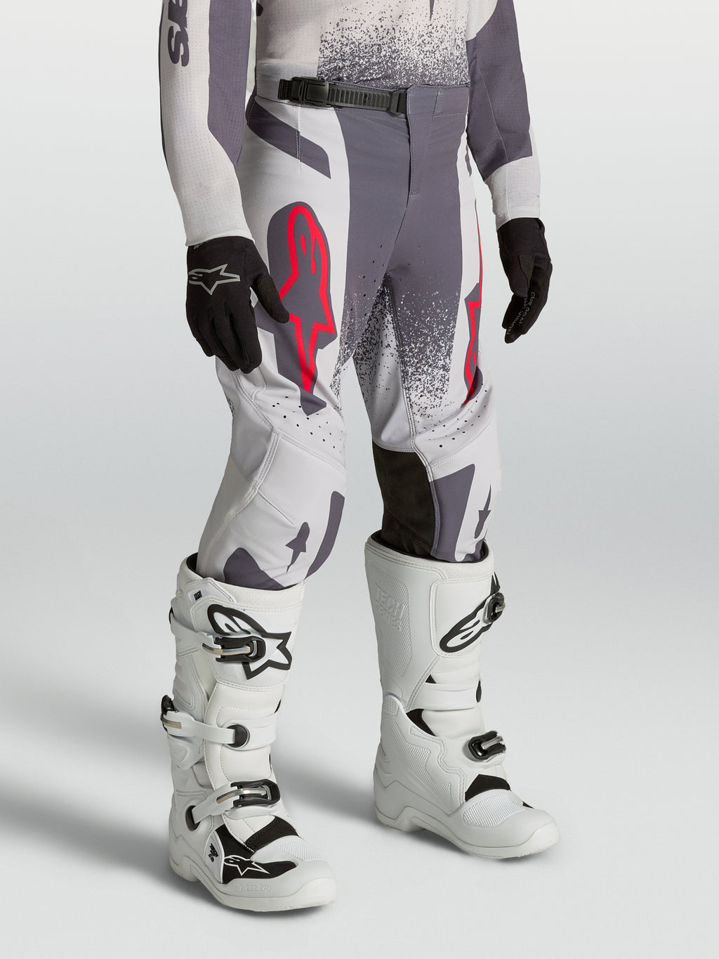 Alpinestars Supertech Swan ungdomsbyxor, grå och ljuslila motocrossbyxor med atletisk passform och röda fluo-detaljer.