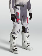 Alpinestars Supertech Swan ungdomsbyxor, grå och ljuslila motocrossbyxor med atletisk passform och röda fluo-detaljer.