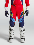 Alpinestars 2027 Supertech Dyna ungdomsbyxor, motocrossbyxor för terrängkörning, röda, marinblå och vita, atletisk passform med 4-vägsstretch, visas på modell med vita stövlar