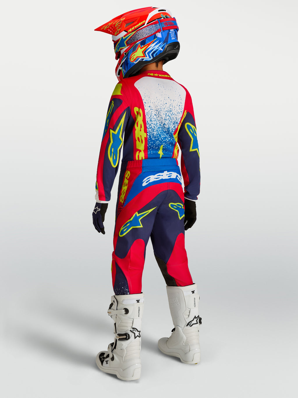 Alpinestars ungdom Fluid Drag-byxor, mörkblå och röda motocrossbyxor med förstärkt säte och vita racingstövlar.