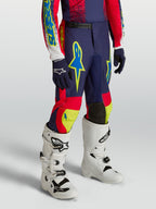 Alpinestars Ungdom Fluid Drag byxor, mörkblå och röda motocrossbyxor med neongula detaljer och vita motorcykelstövlar