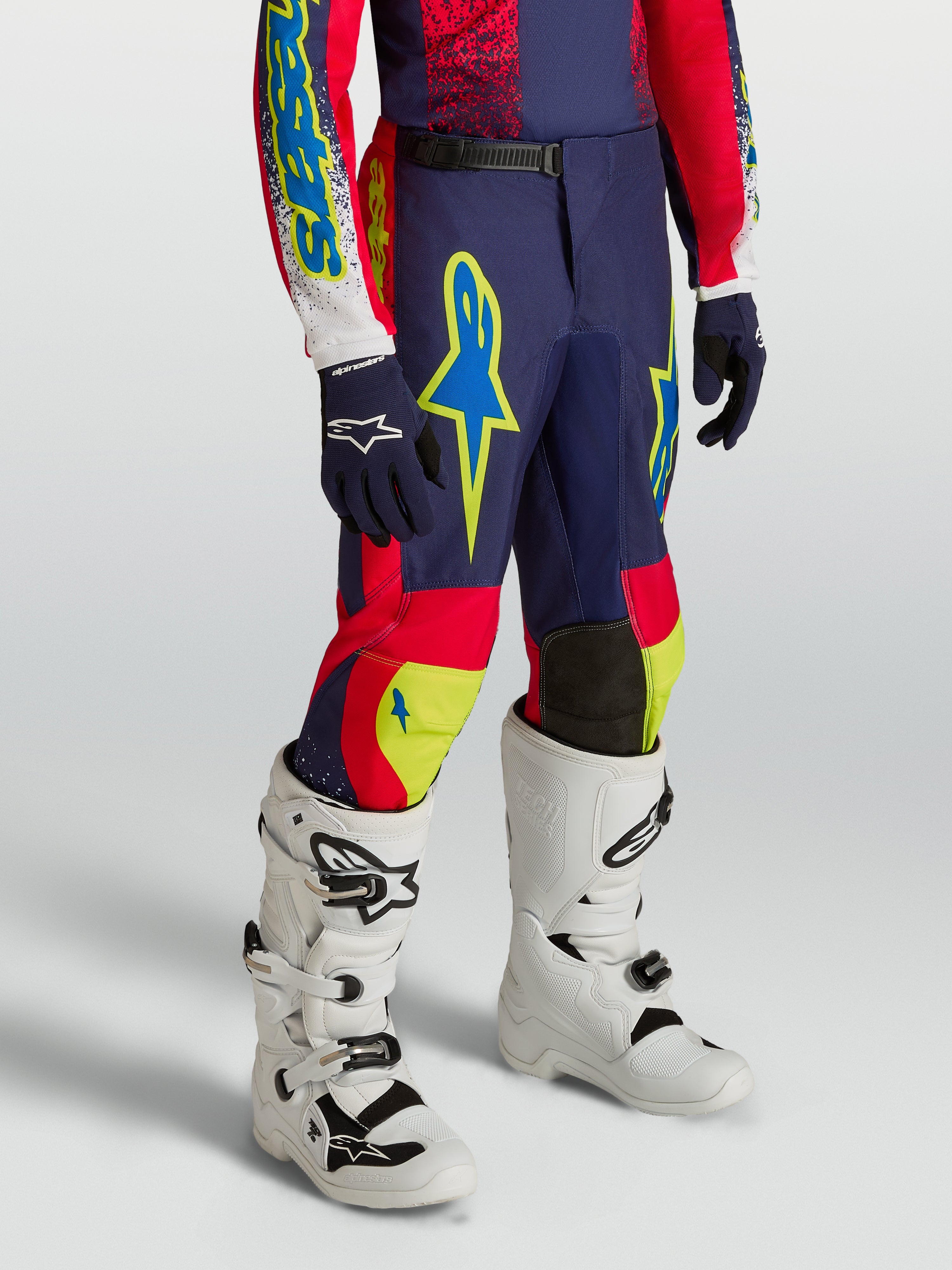 Alpinestars Ungdom Fluid Drag byxor, mörkblå och röda motocrossbyxor med neongula detaljer och vita motorcykelstövlar