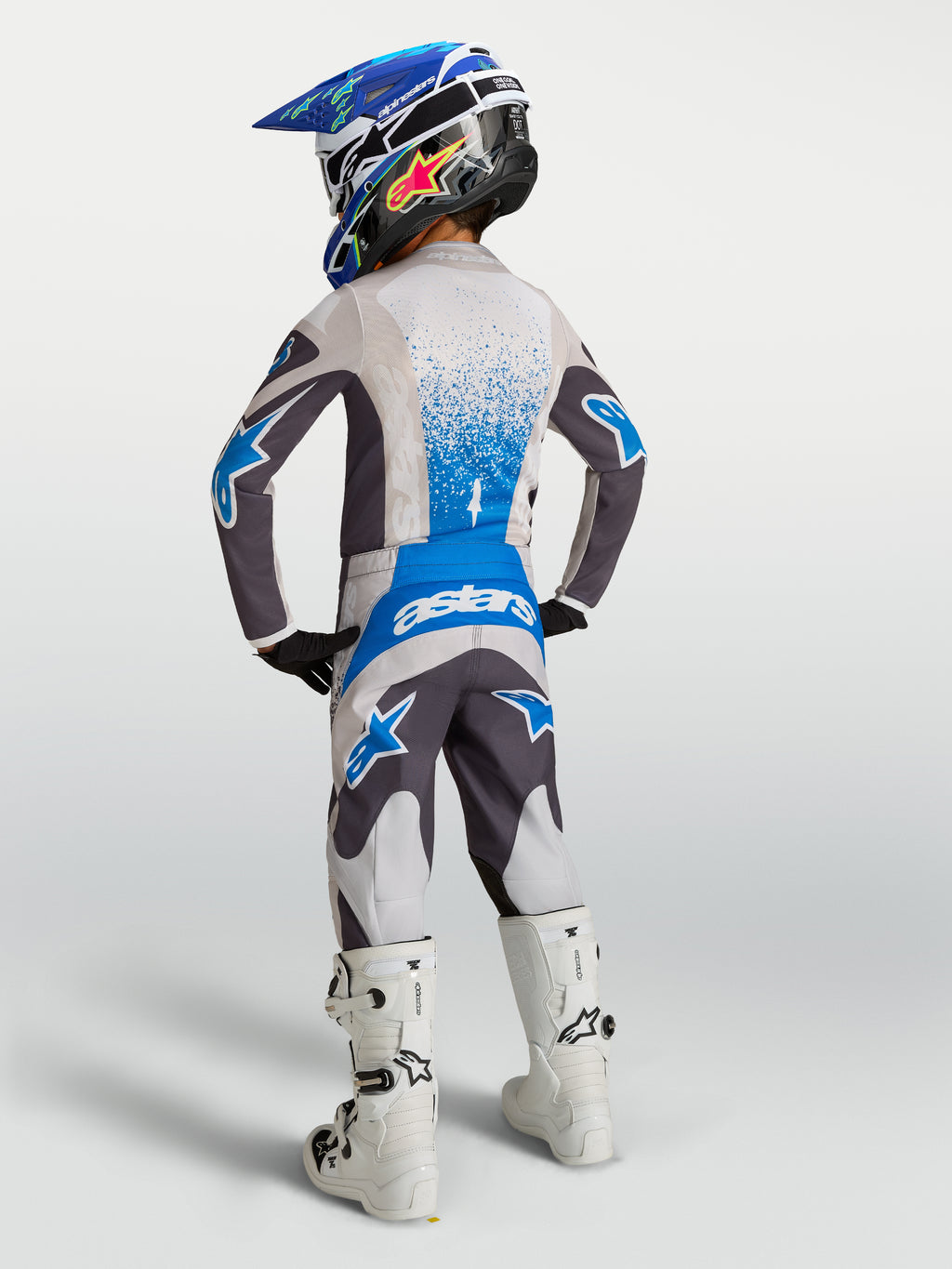 Alpinestars 2027 Ungdom Fluid Drag byxor, grå och blå motocrossbyxor i textil, vy bakifrån på ung förare