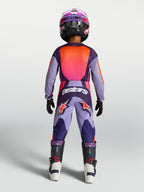 Alpinestars Ungdom Fluid Hunt byxor, motocrossbyxor i lila och rosa, slitstark 600D polytygskonstruktion, vy bakifrån på ung förare i full racingutrustning för terrängkörning.