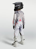 Alpinestars 2027 Ungdom Fluid Lone byxor, grå kamouflage och vita motocrossbyxor med röda detaljer, bakifrån på en förare.