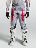 Alpinestars ungdom Fluid Lone byxor, grå camo och röd, på modell med vita stövlar, slitstark polytygskonstruktion.