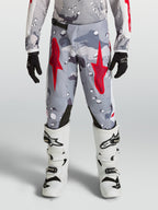 Alpinestars ungdom Fluid Lone byxor, grå camo och röd, på modell med vita stövlar, slitstark polytygskonstruktion.