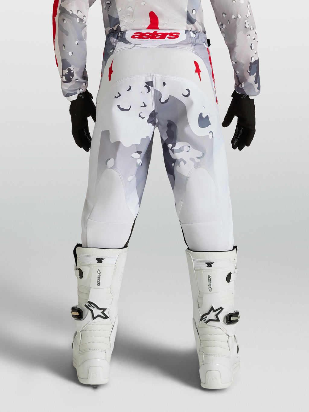 Alpinestars 2027 Ungdom Fluid Lone byxor, grå camo och vita motocrossbyxor med röda detaljer, vy bakifrån på förare.