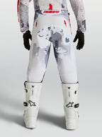 Alpinestars 2027 Ungdom Fluid Lone byxor, grå camo och vita motocrossbyxor med röda detaljer, vy bakifrån på förare.