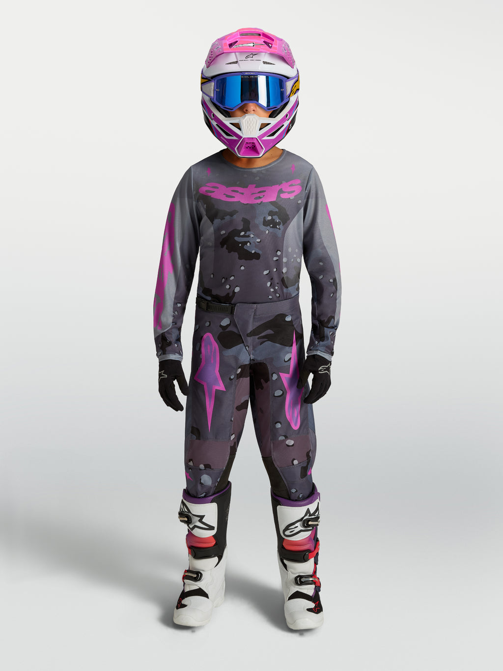 Alpinestars Ungdom Fluid Lone Gear Set, motocross-set för ungdomar i grått och rosa kamouflagemönster, matchande tröja, byxor, hjälm och vita MC-stövlar för terrängkörning.