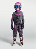 Alpinestars Ungdom Fluid Lone Gear Set, motocross-set för ungdomar i grått och rosa kamouflagemönster, matchande tröja, byxor, hjälm och vita MC-stövlar för terrängkörning.