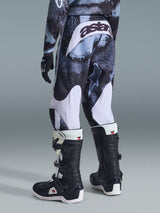 Alpinestars 2026 Youth Fluid Lahnd-byxor, motocrossbyxor, Iron Camo med vita detaljer, vy bakifrån som visar ”astars”-logotyp på sätet, bärs med matchande camotröja och svartvita Tech 3-motocross-stövlar.