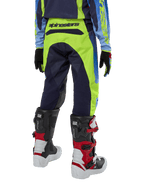 Alpinestars Youth 2024 Racer Hoen byxor, motocrossbyxor, gul fluo och mörkblå (Blue Night Navy), vy bakifrån som visar tydlig Alpinestars-logotyp på linningen, bärs med svarta och röda Tech Series-stövlar och matchande tröja, hållbar sportpassform för terrängkörning för ungdomar
