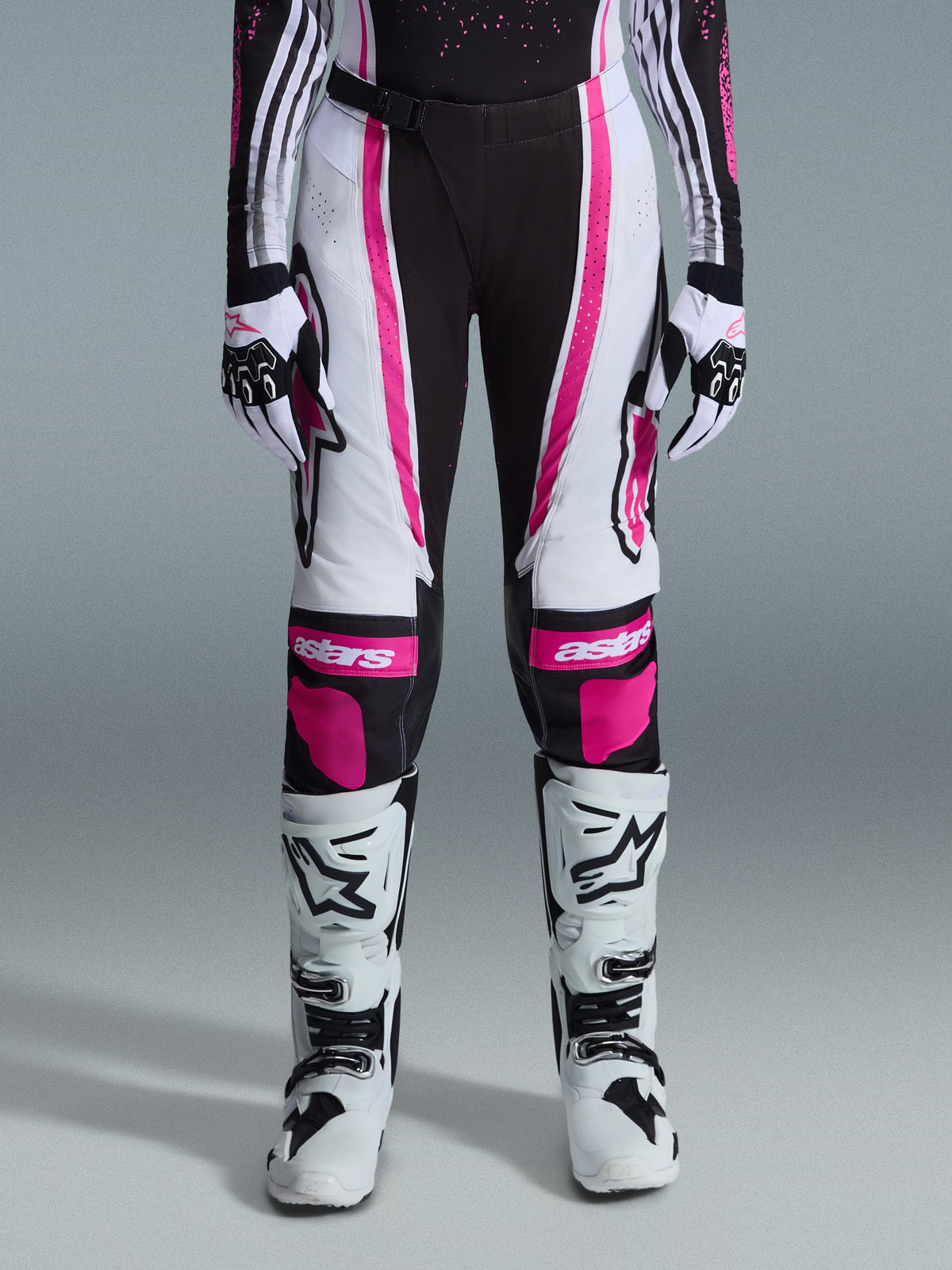 Alpinestars 2026 Stella Techstar Nomur byxor för dam, motocrossbyxor, svart, vit och fuchsia, bärs med matchande racingtröja, handskar och vita motocross-stövlar, med framträdande rosa grafik och astars-logotyper på knäna, designade för terrängtävling på hög nivå.