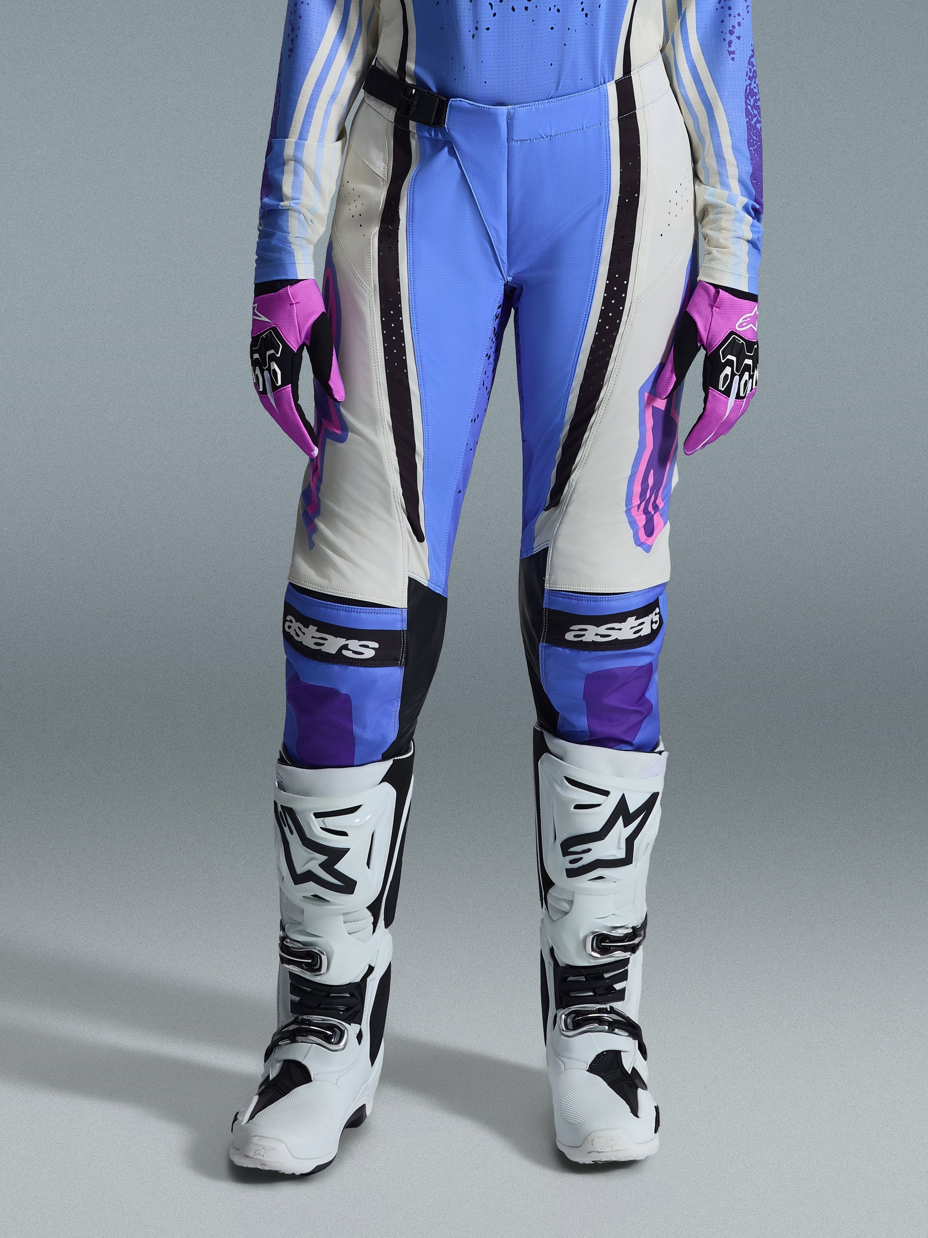 Alpinestars 2026 Stella Techstar Nomur-byxor för dam, motocrossbyxor, ljusblå, off-white och svarta, bärs med vita motocross-stövlar och rosa och svarta handskar, med ”astars”-logotyp på knäna och en teknisk flerpaneldesign för kvinnliga förare.