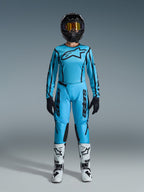 Alpinestars 2026 Stella Fluid Apex utrustningsset, motocrosströja och byxor för dam, blå och svart, med stor stjärnlogotyp på bröstet, bärs med svart hjälm, tonade goggles och vita stövlar med svarta detaljer, komplett outfit för offroadracing