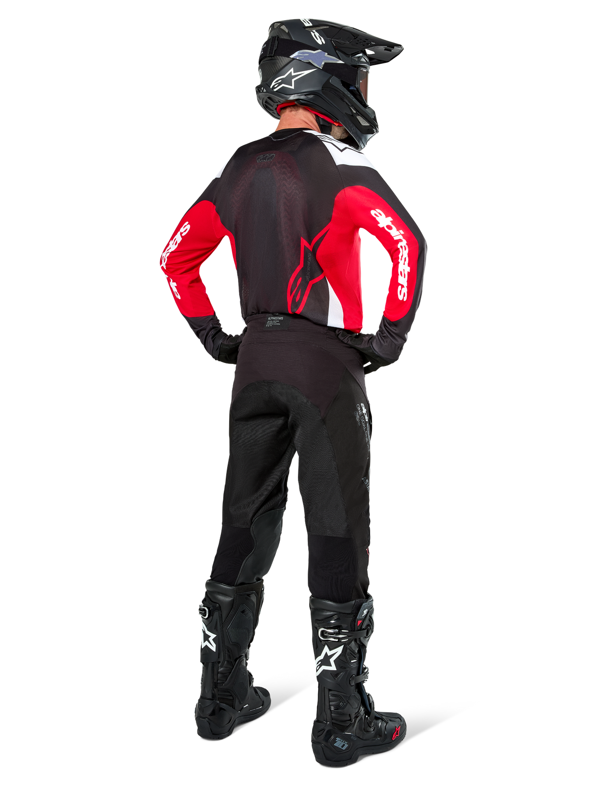 Motocrossförare sedd bakifrån klädd i Alpinestars Pro-Dura-tröja i svart, rött och vitt, matchad med svarta motocrossbyxor, hjälm och stövlar, visar ryggdesignen och ärmlogotyperna, koordinerad utrustning för terrängkörning.
