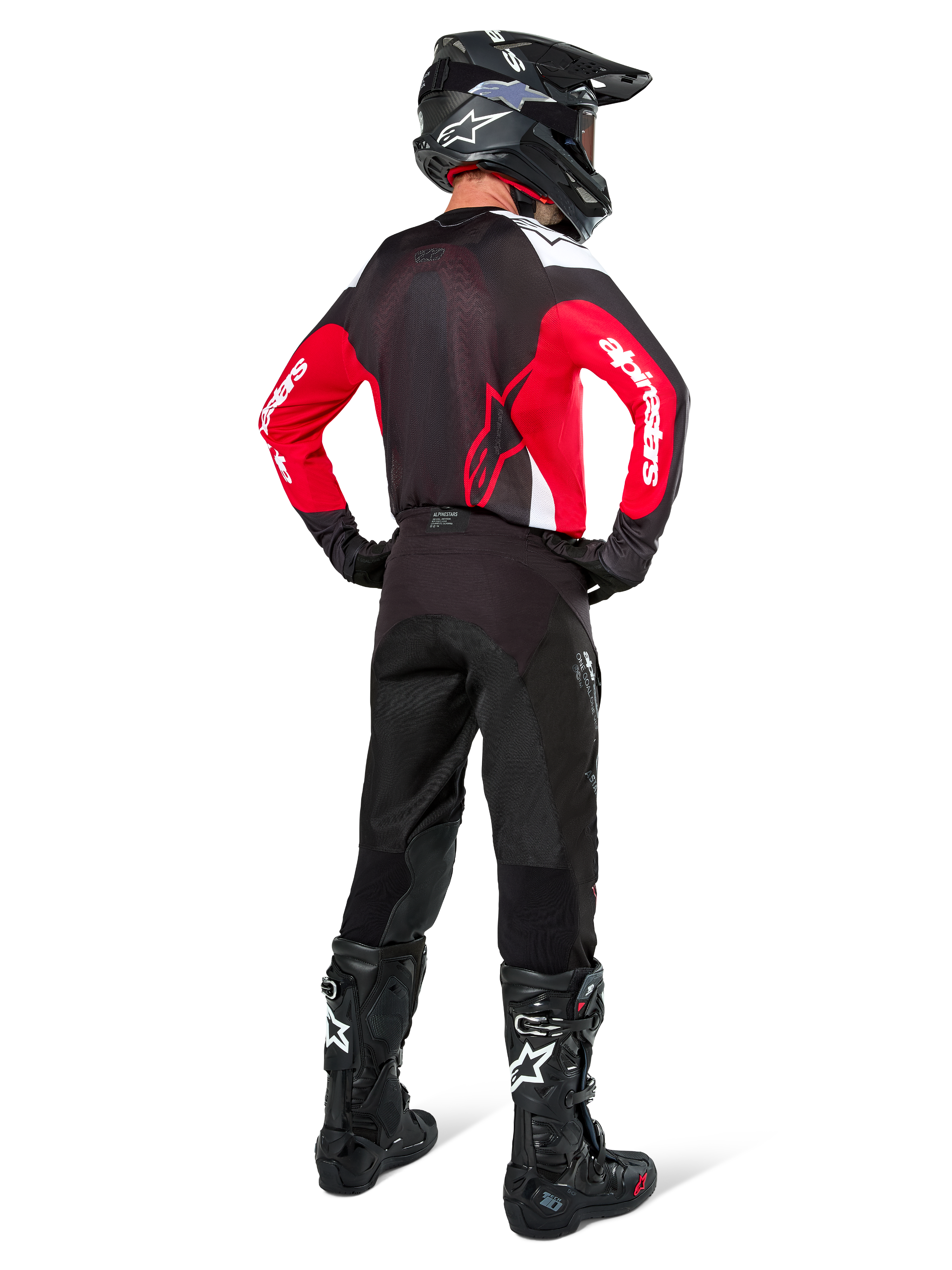 Motocrossförare sedd bakifrån klädd i Alpinestars Pro-Dura-tröja i svart, rött och vitt, matchad med svarta motocrossbyxor, hjälm och stövlar, visar ryggdesignen och ärmlogotyperna, koordinerad utrustning för terrängkörning.