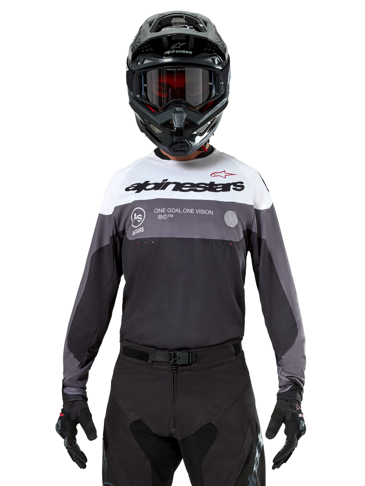 Motocrossförare som bär Alpinestars Pro-Dura Jersey i Black Magnet White, långärmad funktionströja med vita och grå färgblock, svart hjälm och goggles, 'alpinestars'-branding och slogan 'ONE GOAL ONE VISION', offroad-racingkläder