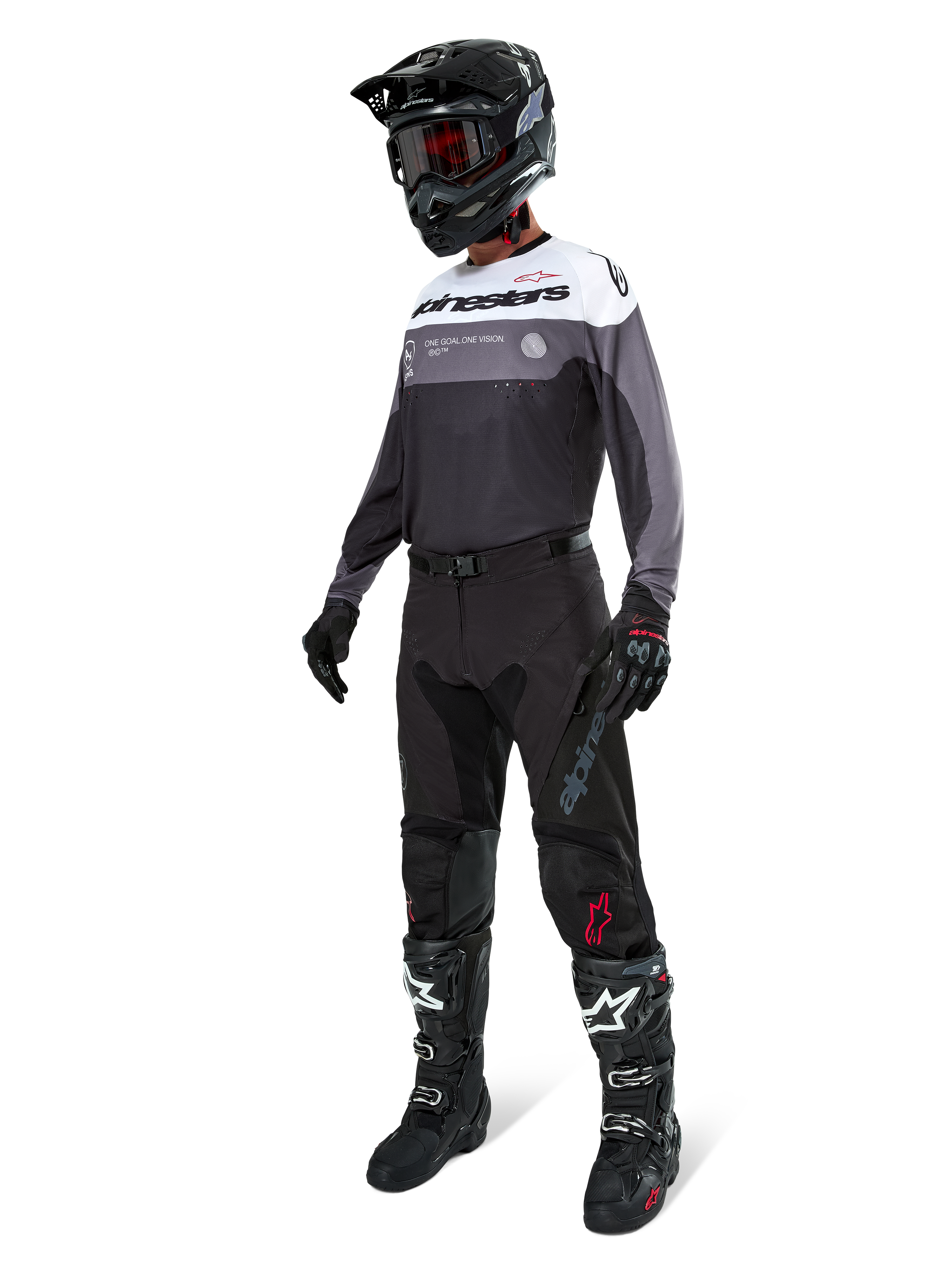 Alpinestars Pro-Dura-tröja i Black Magnet White, bärs av en motocrossförare i komplett utrustning inklusive svarta byxor, svart hjälm med goggles och svartvita stövlar. Tröjan har en teknisk färgblocksdesign med vita, grå och svarta paneler, konstruerad för enduro- och offroad-prestanda.