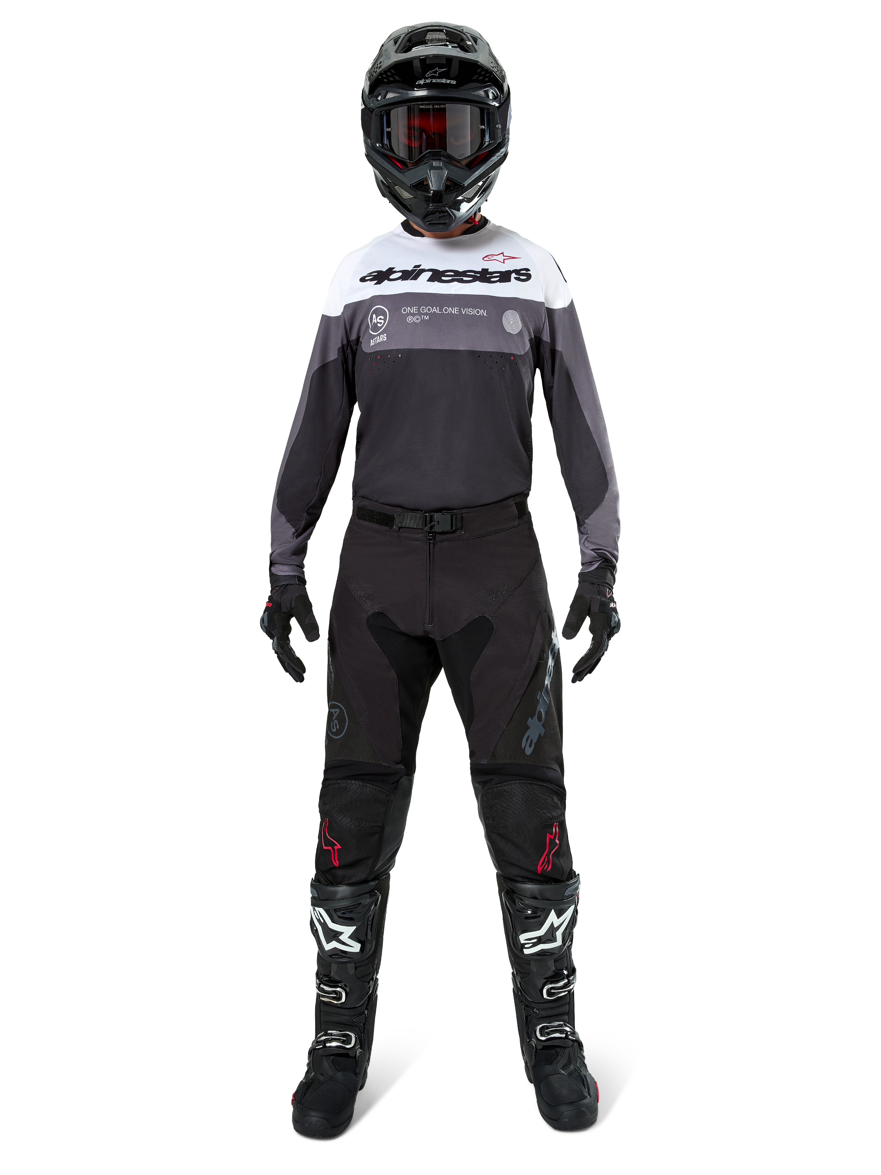 Motocrossförare i komplett racingutrustning, Pro-Dura Jersey i Black Magnet White med vitt övre bröstparti och grå detaljer, matchad med svarta byxor, svart hjälm med mörka goggles, vita och svarta stövlar och svarta handskar, koordinerad outfit för enduro och terrängkörning