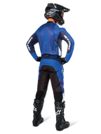 Motocross rider from the back wearing Alpinestars Pro-Dura Jersey in Navy and Bright Blue, matching blue and black pants, black motocross helmet with goggles, and black boots, showing a coordinated off-road racing outfit