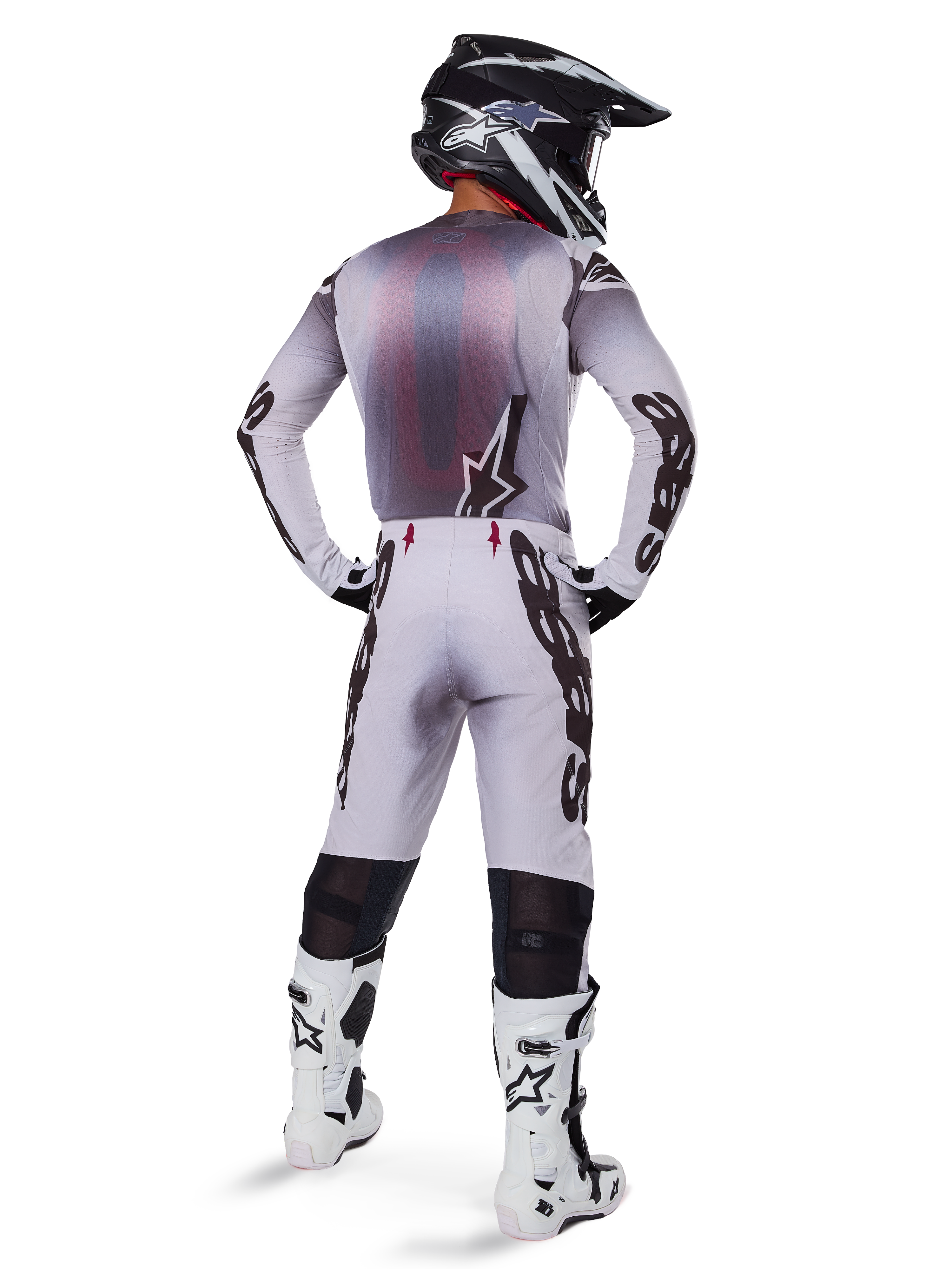 Motocross rider viewed from the back wearing the 2025 Supertech Maker Gear Set in White, featuring a grey and white jersey with black Alpinestars branding, matching motocross pants, white and black boots, and a black helmet, coordinated off-road racing kit