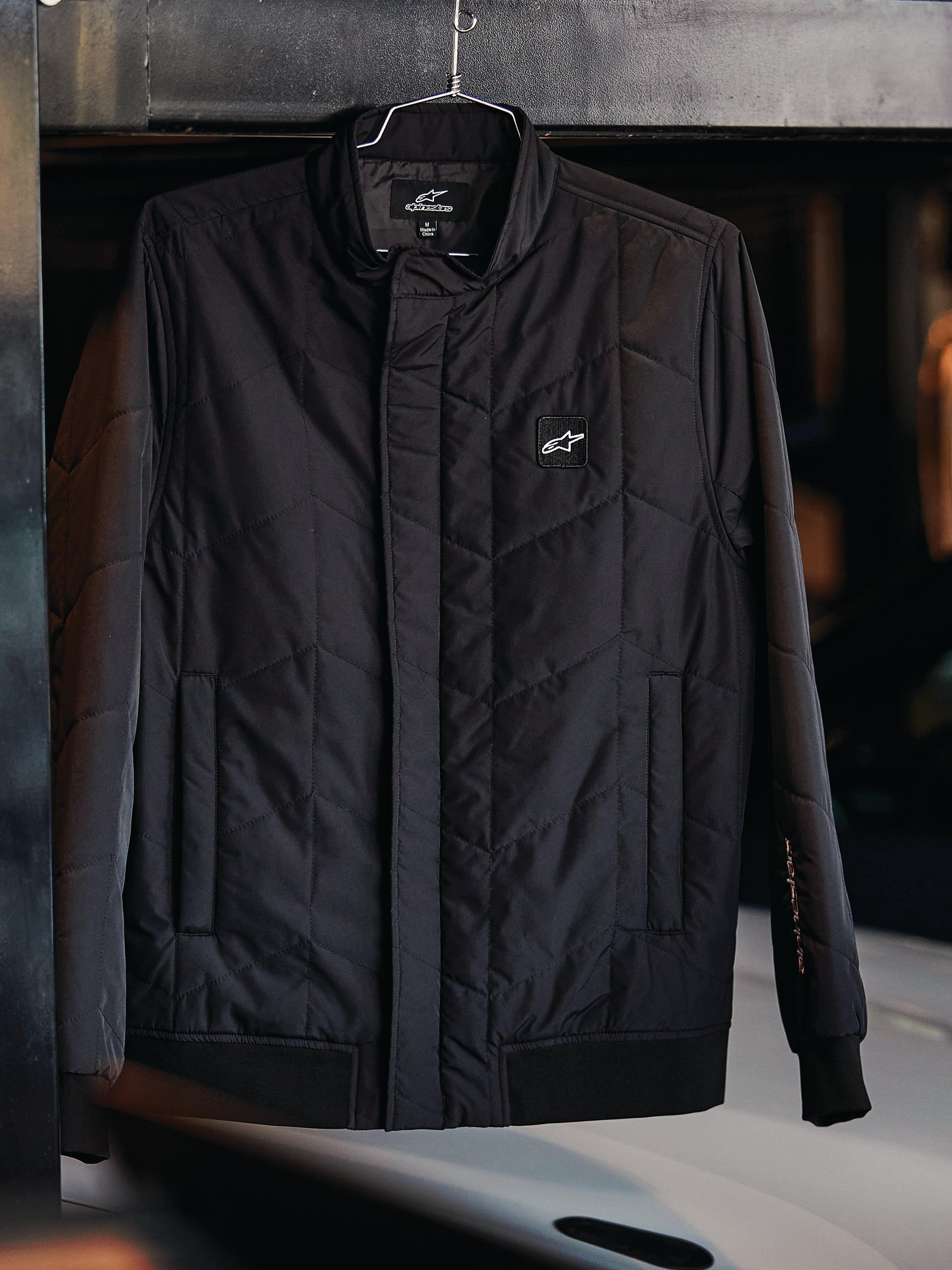 Alpinestars Precedent-jacka, quiltad sportswear-jacka, svart, med vinklat quiltmönster, låg ståkrage med täckt dragkedja, logomärke på bröstet, ribbade muddar och nederkant, motorsport-inspirerad design