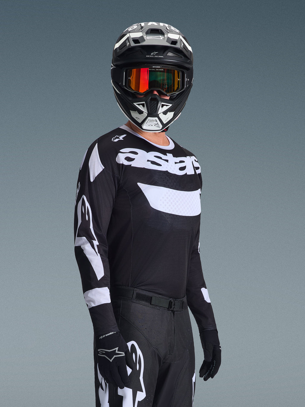 Motocrossförare som bär 2026 Racer Air Riway Jersey, svart och vit tröja med "astars"-logotyp, matchande svart och vit hjälm med orangea spegelglasgoggles, svarta motocrossbyxor och handskar, koordinerad outfit för terrängkörning