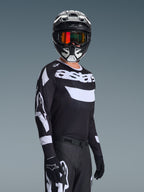 Motocrossförare som bär 2026 Racer Air Riway Jersey, svart och vit tröja med "astars"-logotyp, matchande svart och vit hjälm med orangea spegelglasgoggles, svarta motocrossbyxor och handskar, koordinerad outfit för terrängkörning
