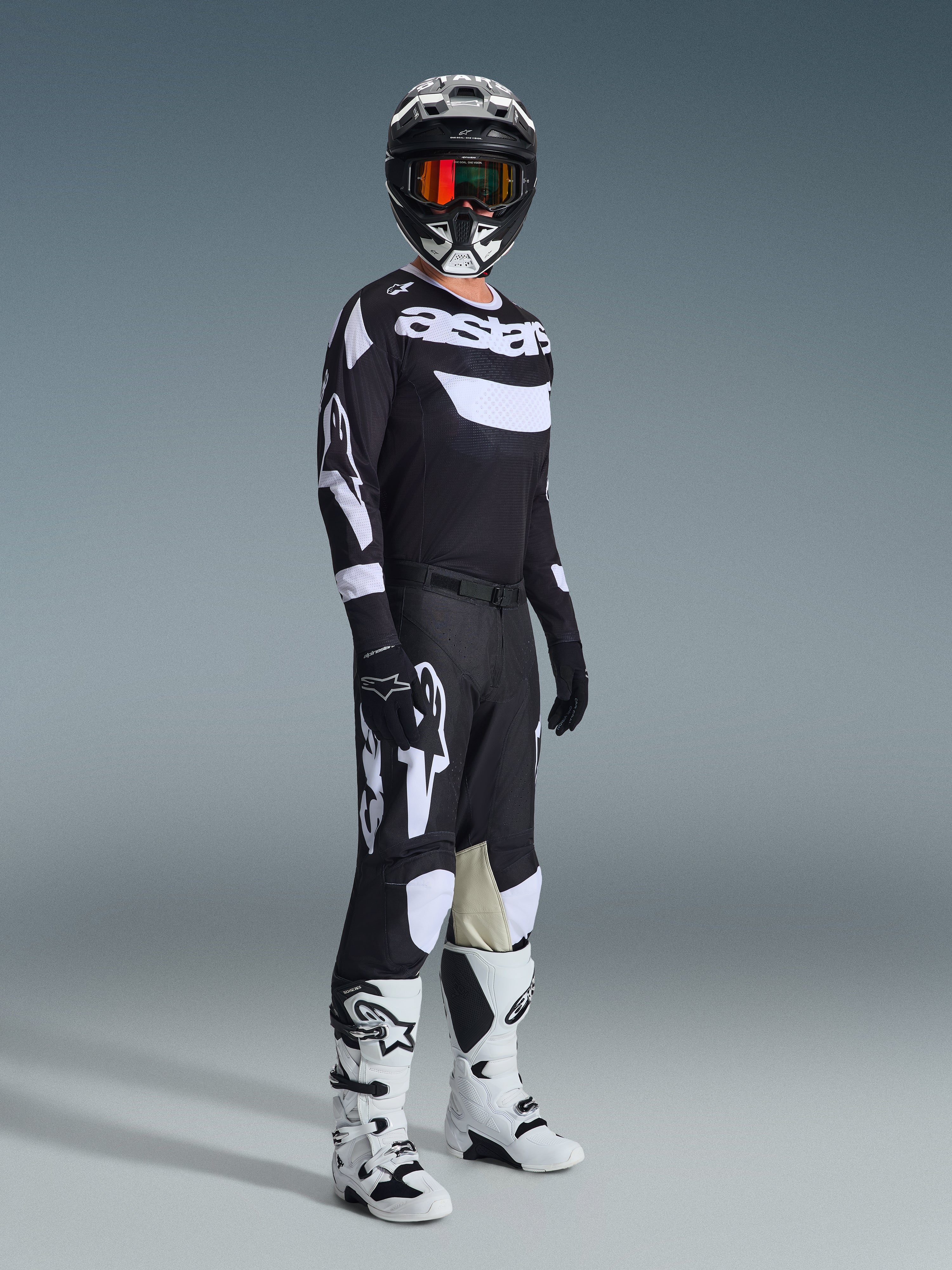 Alpinestars 2026 Racer Air Riway Gear Set, Motocross rider wearing complete racing gear, Black jersey with white 'Astars' branding and mesh panels, black pants with large white logos and knee panels, black helmet with red goggles, white and black boots, professional off-road racing outfit.
