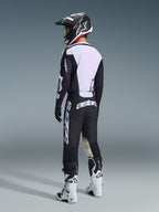 Motocrossförare sedd bakifrån bärande 2026 Racer Air Riway Jersey i svart och vitt, som visar den stora vita meshpanelen på ryggen för luftflöde, matchat med svarta byxor, svartvit hjälm och vita racingstövlar, komplett professionell utrustning för terrängkörning.