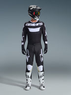 Motocrossförare iklädd komplett racingutrustning, Alpinestars 2026 Racer Air Riway-tröja i svart och vitt med 'astars'-logotyp på bröstet, matchande svarta byxor med vita detaljer, vita motocross-stövlar samt svart och vit hjälm med goggles, koordinerad professionell outfit för terrängkörning