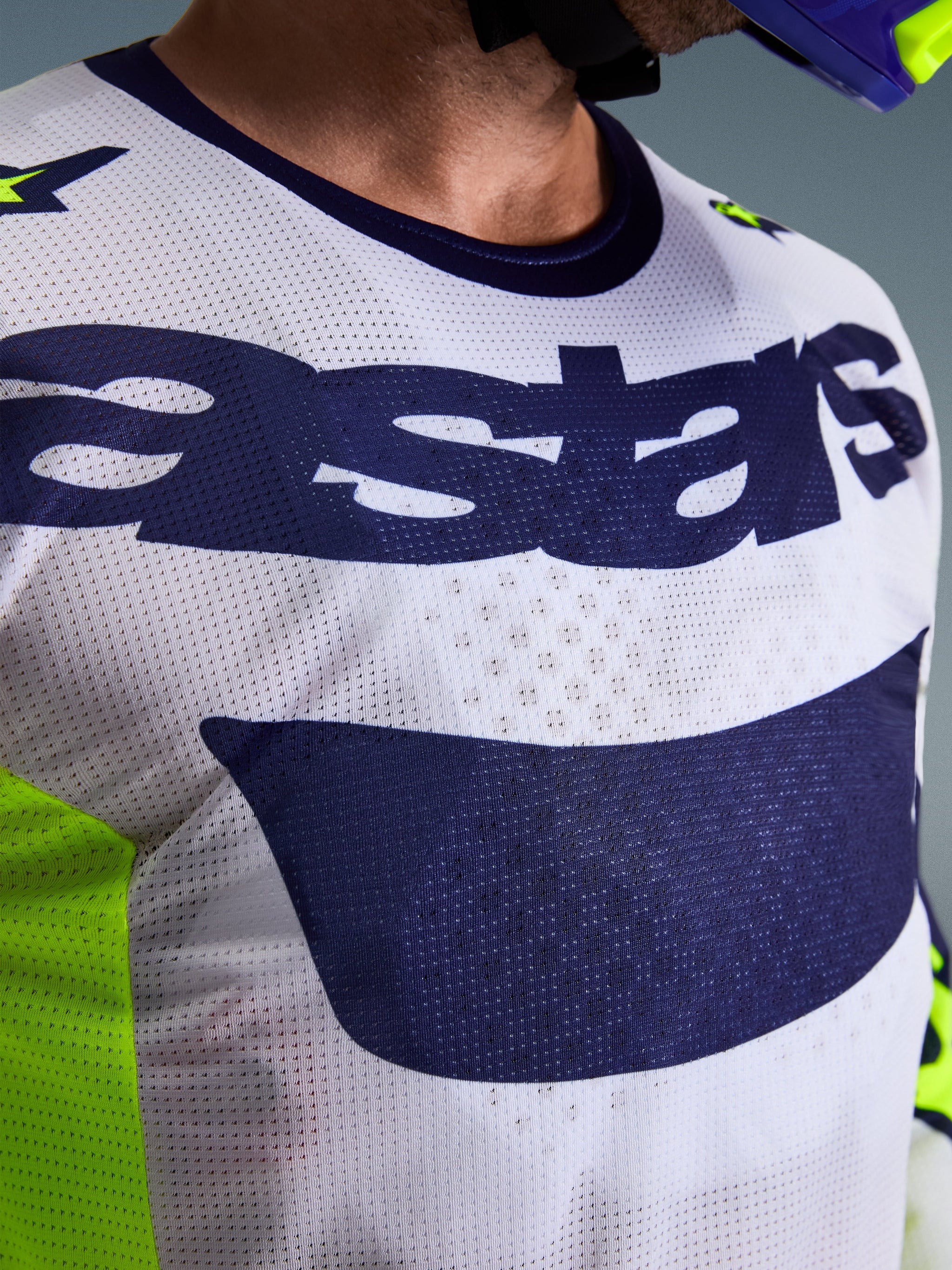 Alpinestars 2026 Racer Air Riway-tröja, motocross-tröja, ljusgrå och marinblå med neongula detaljer, närbild på bröstet som visar 'astars'-logotypen och perforerat meshtyg, atletisk passform för terrängkörning