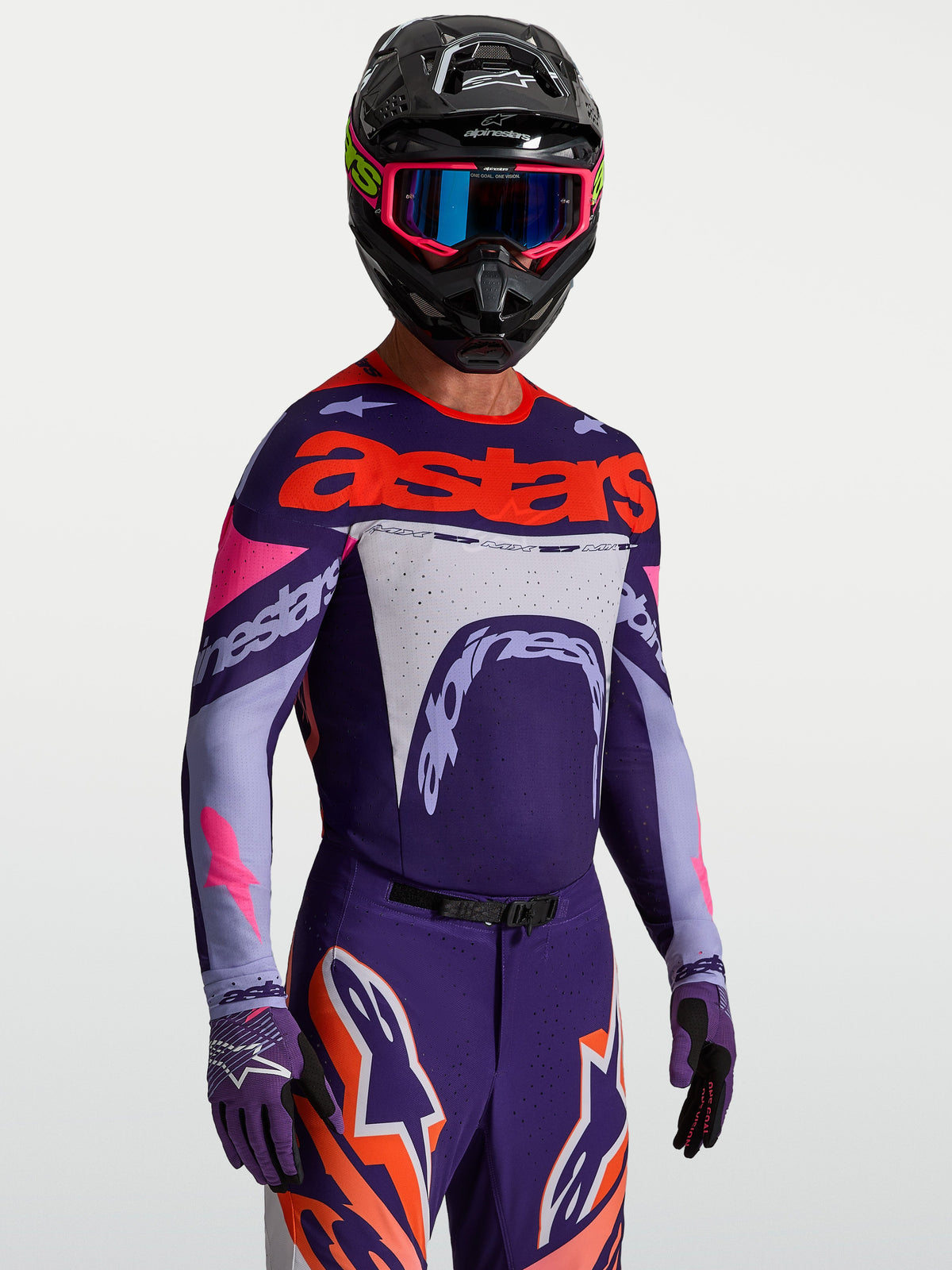 Alpinestars Supertech Dyna-tröja, lila och neonrosa motocrosströja för herrar, stretchmesh, bärs av modell med hjälm.