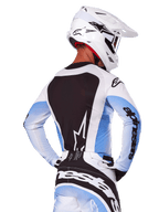 Rear view of a motocross rider wearing the Alpinestars 2025 Techstar Melt Gear Set in White and Blue, jersey featuring a large black back panel with a white star logo and light blue gradient sleeves, matching white and blue pants, white racing helmet, and black and white gloves, coordinated performance gear for motocross