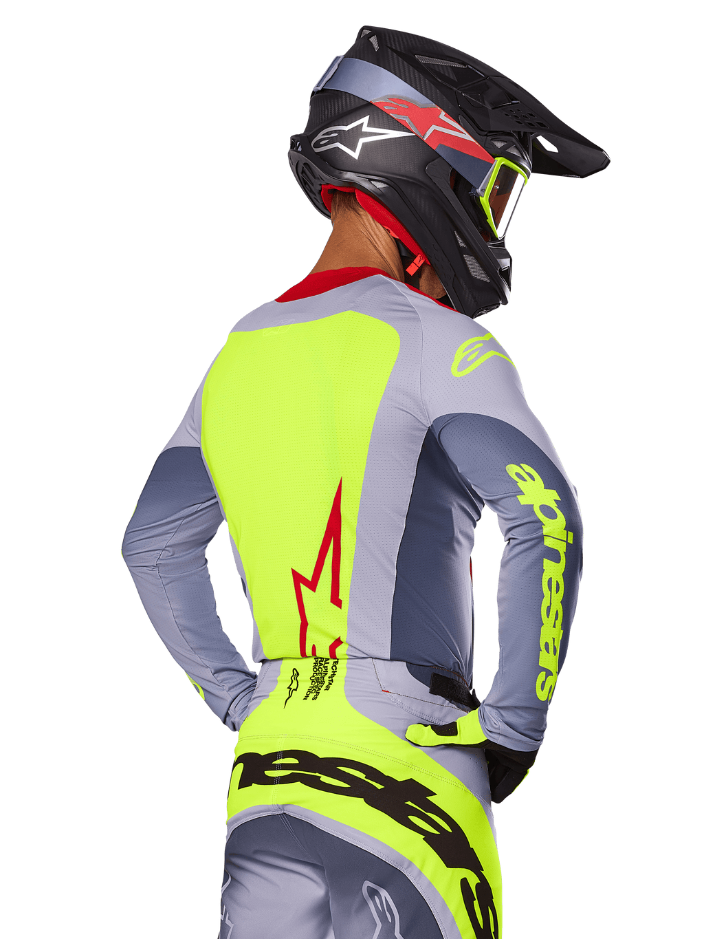 Alpinestars 2025 Techstar Melt-tröja, Bright Red Gray, vy bakifrån av motocrossförare i grå och neongul racingutrustning, röd stjärnlogotyp på ryggen, matchande svart och röd hjälm, högpresterande terrängkläder