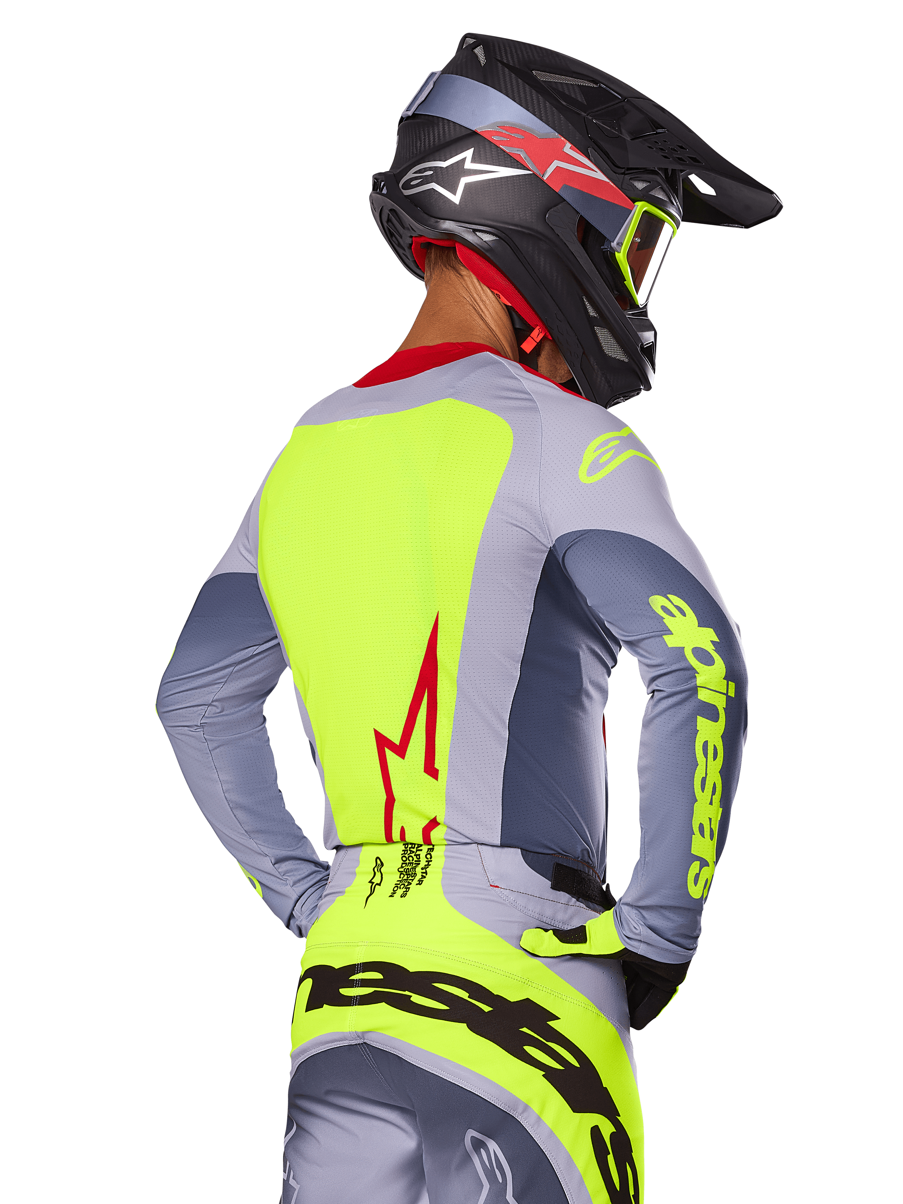 Alpinestars 2025 Techstar Melt-tröja, Bright Red Gray, vy bakifrån av motocrossförare i grå och neongul racingutrustning, röd stjärnlogotyp på ryggen, matchande svart och röd hjälm, högpresterande terrängkläder