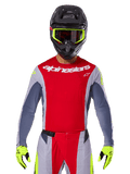 Motocrossförare klädd i 2025 Techstar Melt-tröja och matchande byxor, röd och grå med vit Alpinestars-logotyp, svart hjälm med neongula goggles, matchande neongula handskar, ventilerad prestandautrustning för terrängkörning