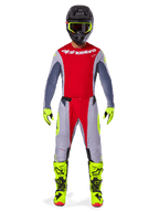 Motocrossförare i Alpinestars 2025 Techstar Melt utrustningsset, röd tröja med grå ärmar och vit logotyp, matchande grå och röda byxor, neongula goggles, handskar och stövlar, komplett motocrossoutfit för terrängkörning