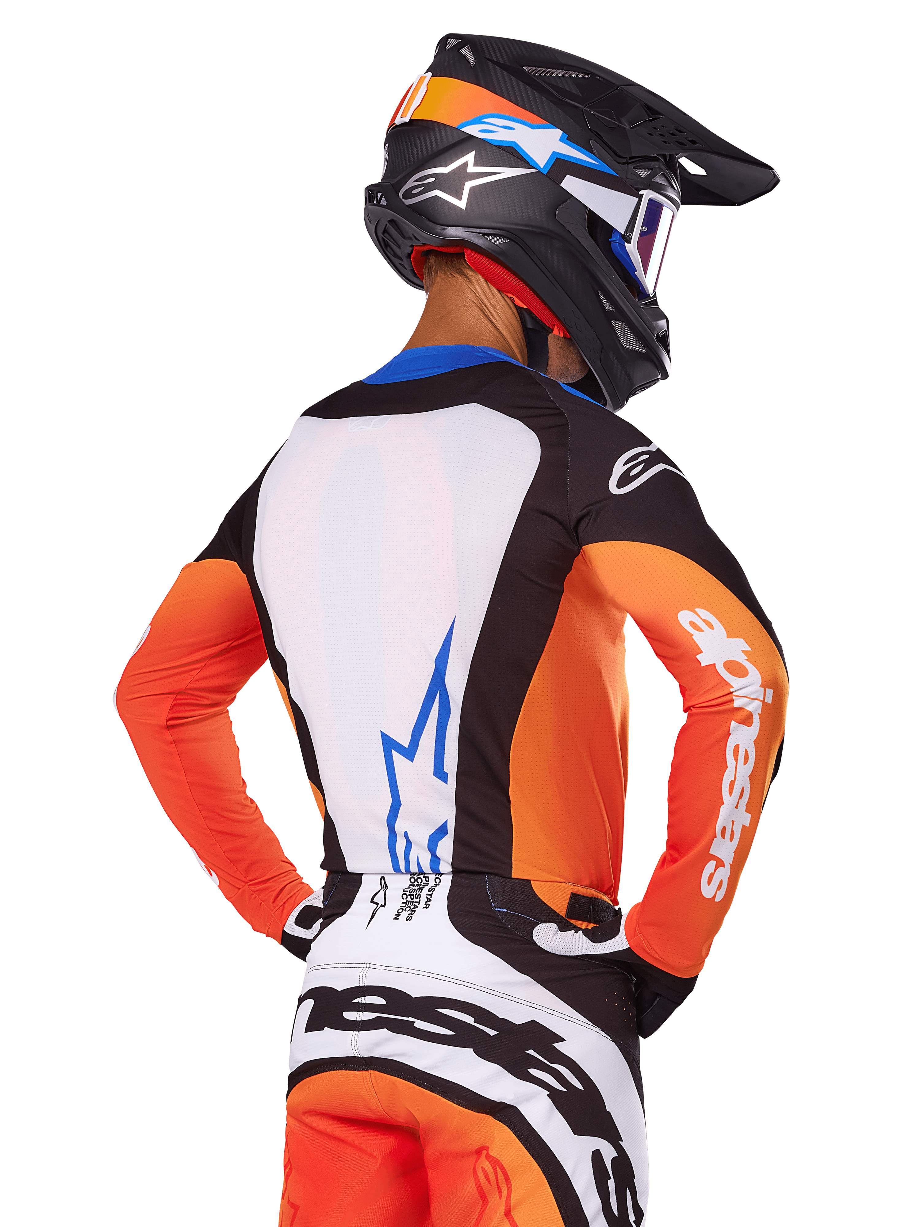 Motocrossförare i Alpinestars 2025 Techstar Melt Jersey, orange och blå, vy bakifrån som visar vit ryggpanel med blå logotyp, orangea ärmar med vit logotyp, matchande motocrosshjälm och byxor, professionell racingutrustning.