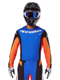 Alpinestars 2025 Techstar Melt-tröja, motocrosströja, blå och orange med svarta sidopaneler, bärs med svart hjälm och blå goggles, med ventilerande laserskurna perforeringar på bröstet, atletisk racingpassform för offroad-prestanda