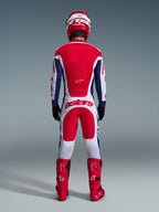 Motocrossförare sedd bakifrån i komplett racingutrustning, Alpinestars 2026 Racer Riway-tröja i White Blue Red, matchande vita och röda byxor med framträdande "astars"-logotyp, röda stövlar och röd och vit hjälm, koordinerad outfit för terrängkörning.