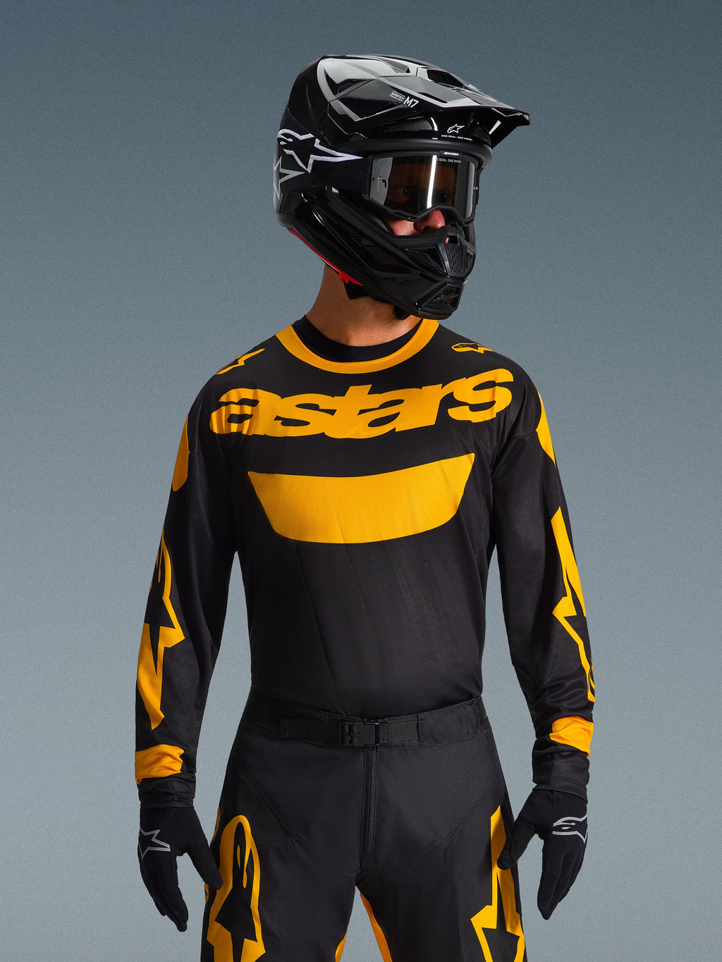Alpinestars 2026 Racer Riway Gear Set, motocrossförare i svart tröja med framträdande gul 'astars'-logotyp, matchande svarta byxor med gula detaljer, svart hjälm och goggles, svarta handskar, professionell racingutrustning för terrängkörning