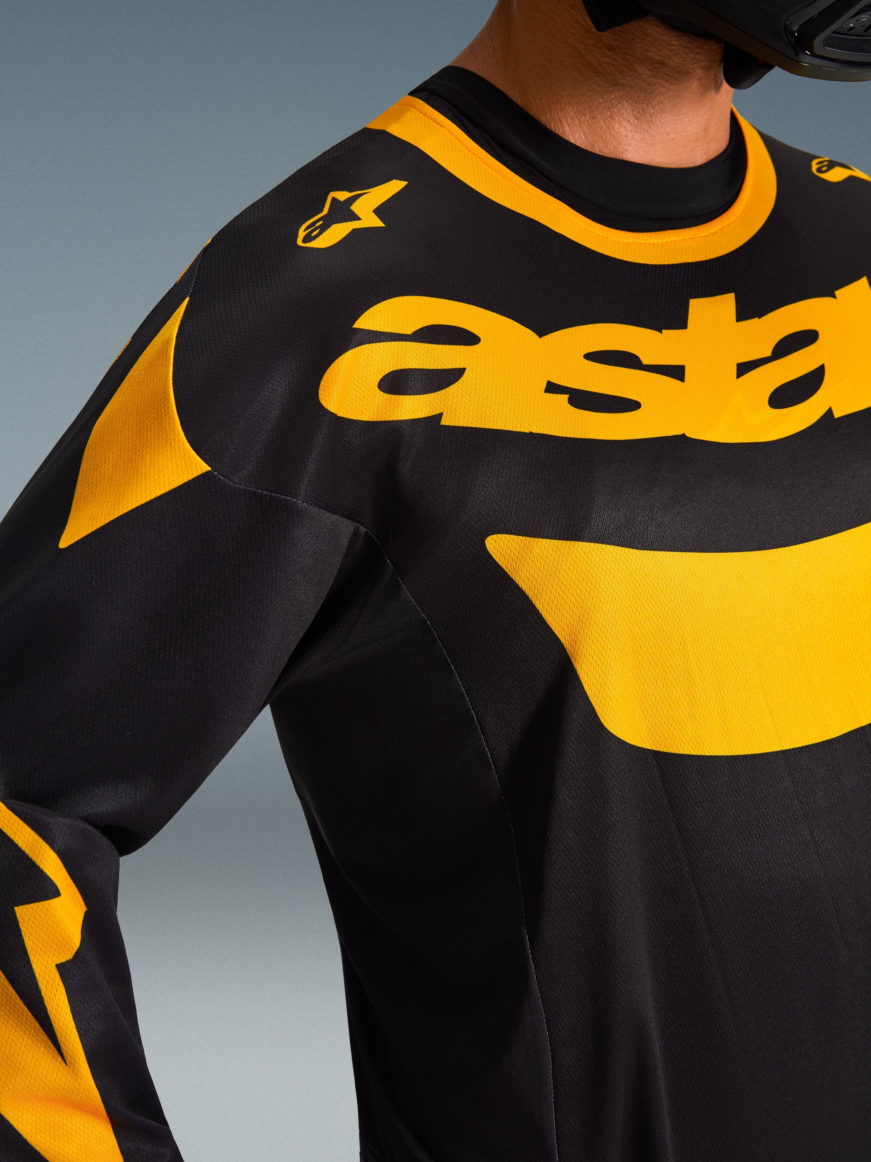 Närbild på Alpinestars 2026 Racer Riway Jersey, svart och gul, med framträdande gul logotyp över bröstet, teknisk mesh-konstruktion för ventilation, högpresterande motocrosskläder