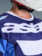 Alpinestars 2026 Racer Riway Jersey, Motocross Jersey, Ucla Blue and White, close-up view of chest featuring large white 'astars' branding, white collar, and moisture-wicking mesh texture, worn with a white helmet