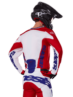 Alpinestars 2025 Racer Veil tröja och byxor, motocross-utrustningsset, klarröd, vit och blå, vy bakifrån av förare i matchande ställ och svart motocrosshjälm, framträdande blå Alpinestars-profilering, teknisk utrustning för offroad-racing