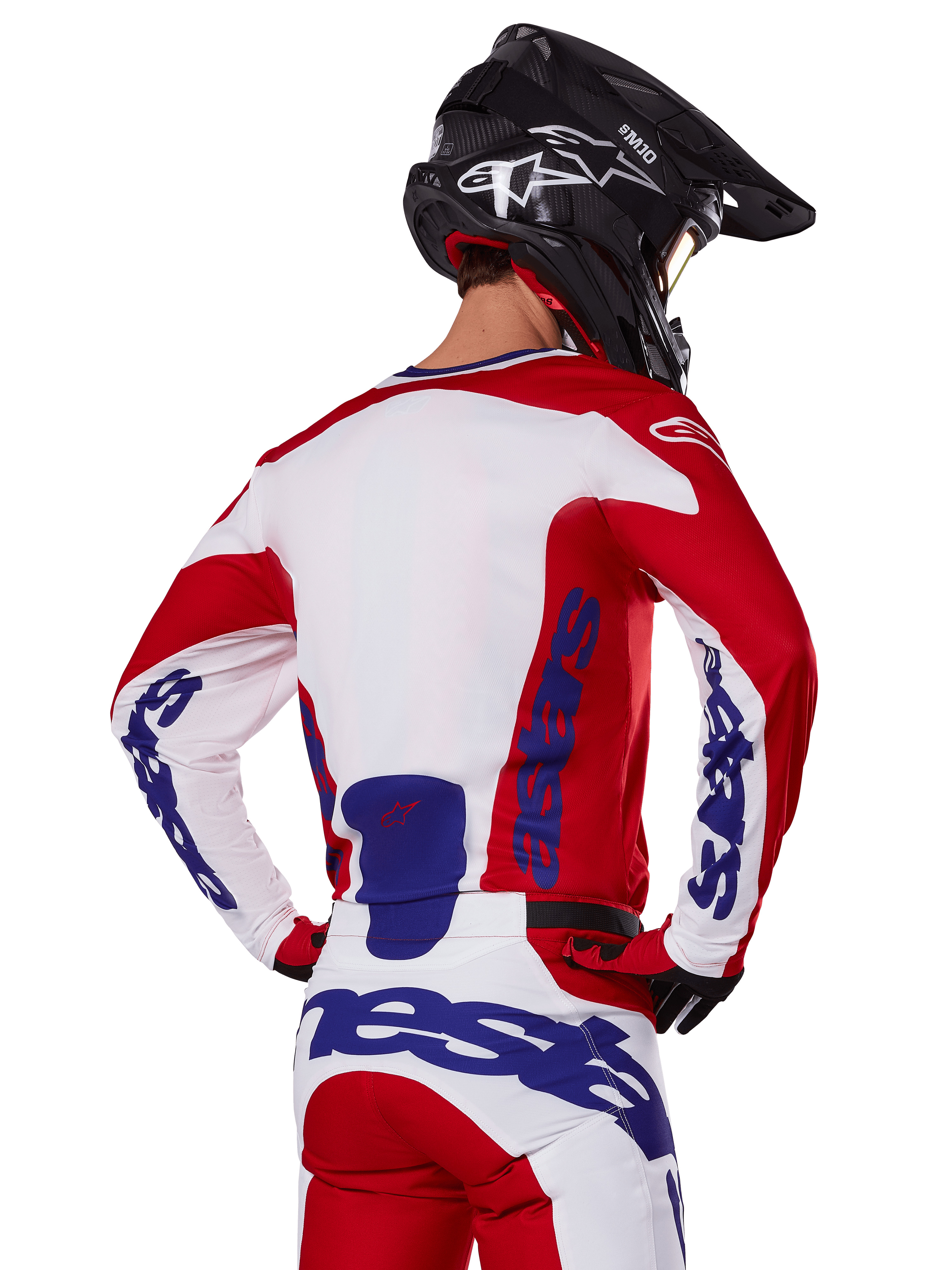Alpinestars 2025 Racer Veil tröja och byxor, motocross-utrustningsset, klarröd, vit och blå, vy bakifrån av förare i matchande ställ och svart motocrosshjälm, framträdande blå Alpinestars-profilering, teknisk utrustning för offroad-racing
