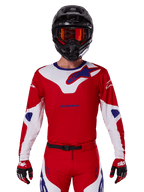 Alpinestars 2025 Racer Veil tröja, motocross-racingtröja, röd, vit och blå, långärmad, bärs med svart hjälm och orangefärgade goggles, matchande röda handskar och byxor, strömlinjeformad prestandadesign för terrängkörning